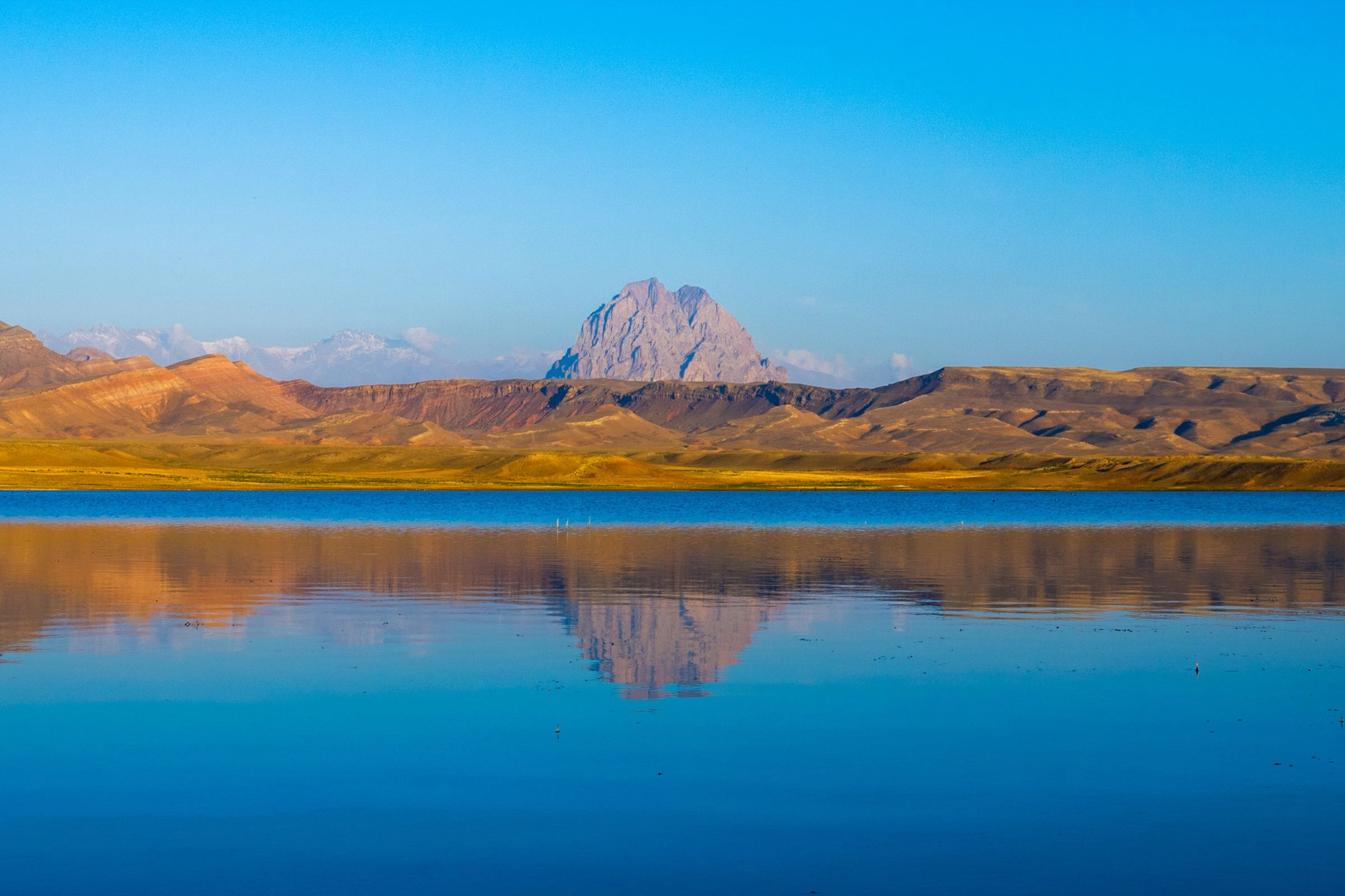 Clear blue Bənəniyar Reservoir reflecting mountains under bright skies in Nakhchivan.