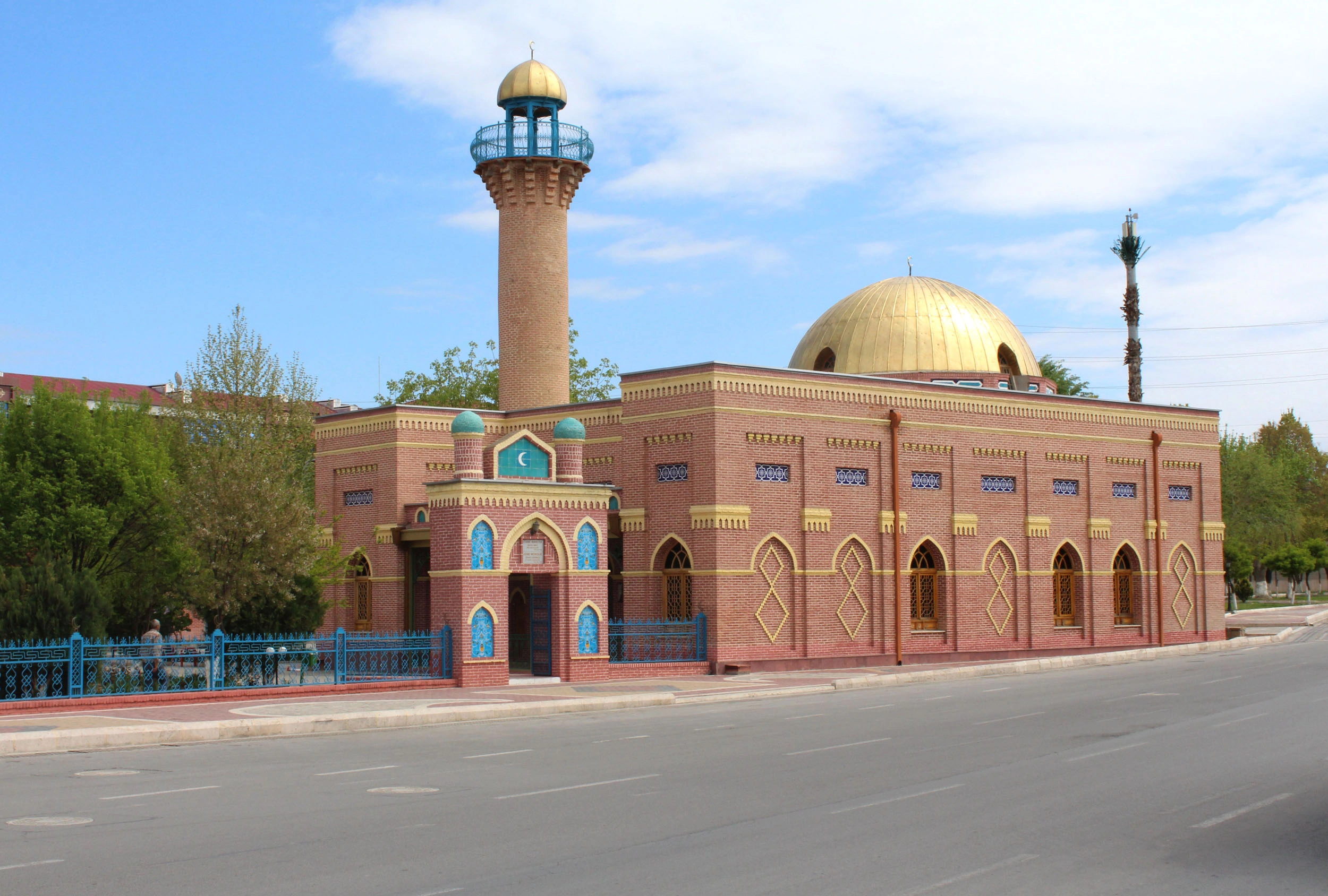 Came Mosque in Nakhchivan with golden dome and red-brick facade under a soft sky.
