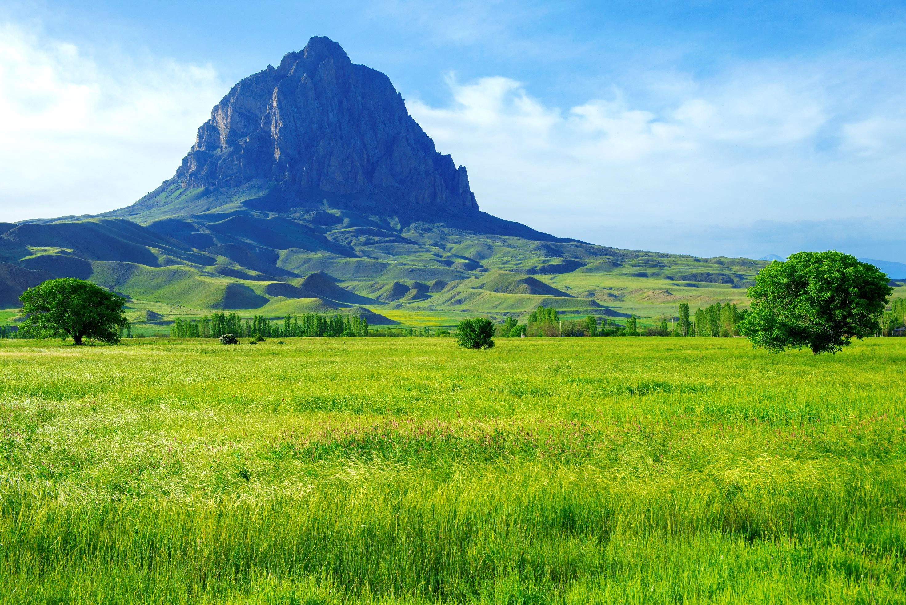 Haçadağ Mountain rises over lush Nakhchivan meadows under a bright blue sky.
