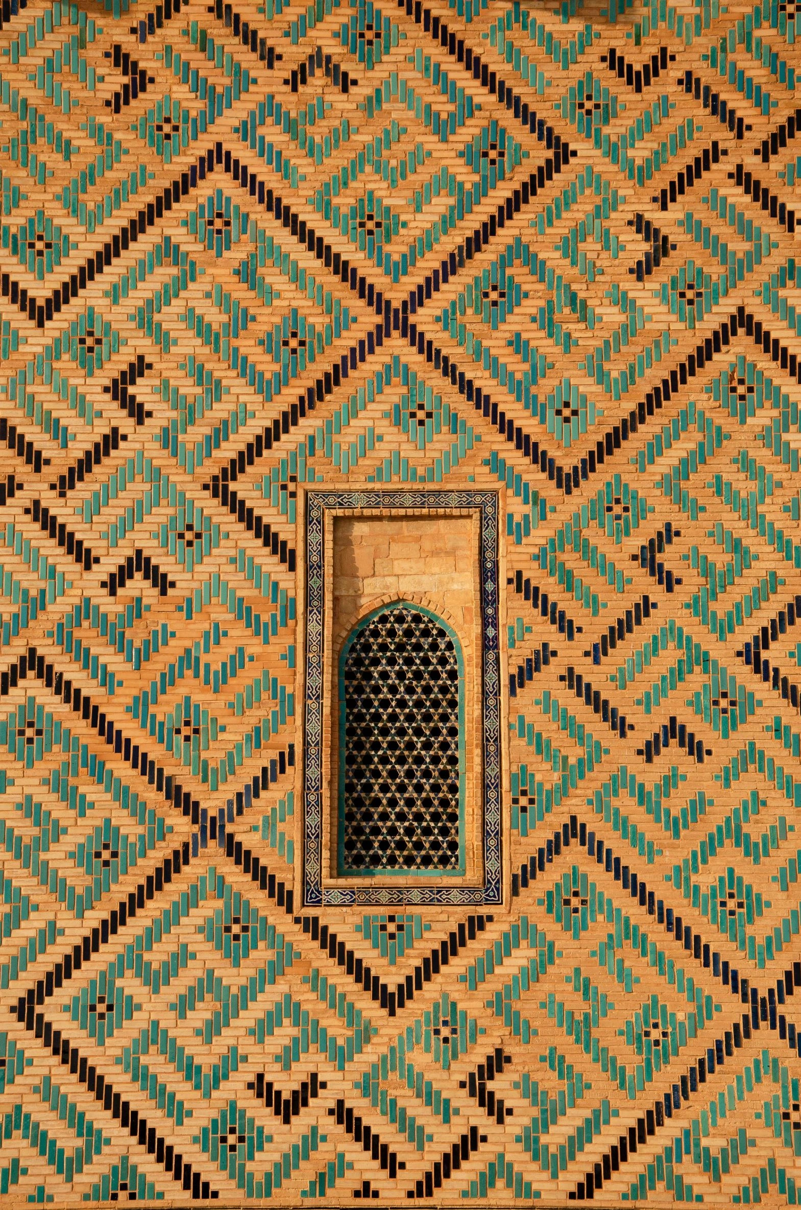 Close-up of colorful mosaic brick wall with arched window from Yasawi Mausoleum, Kazakhstan.
