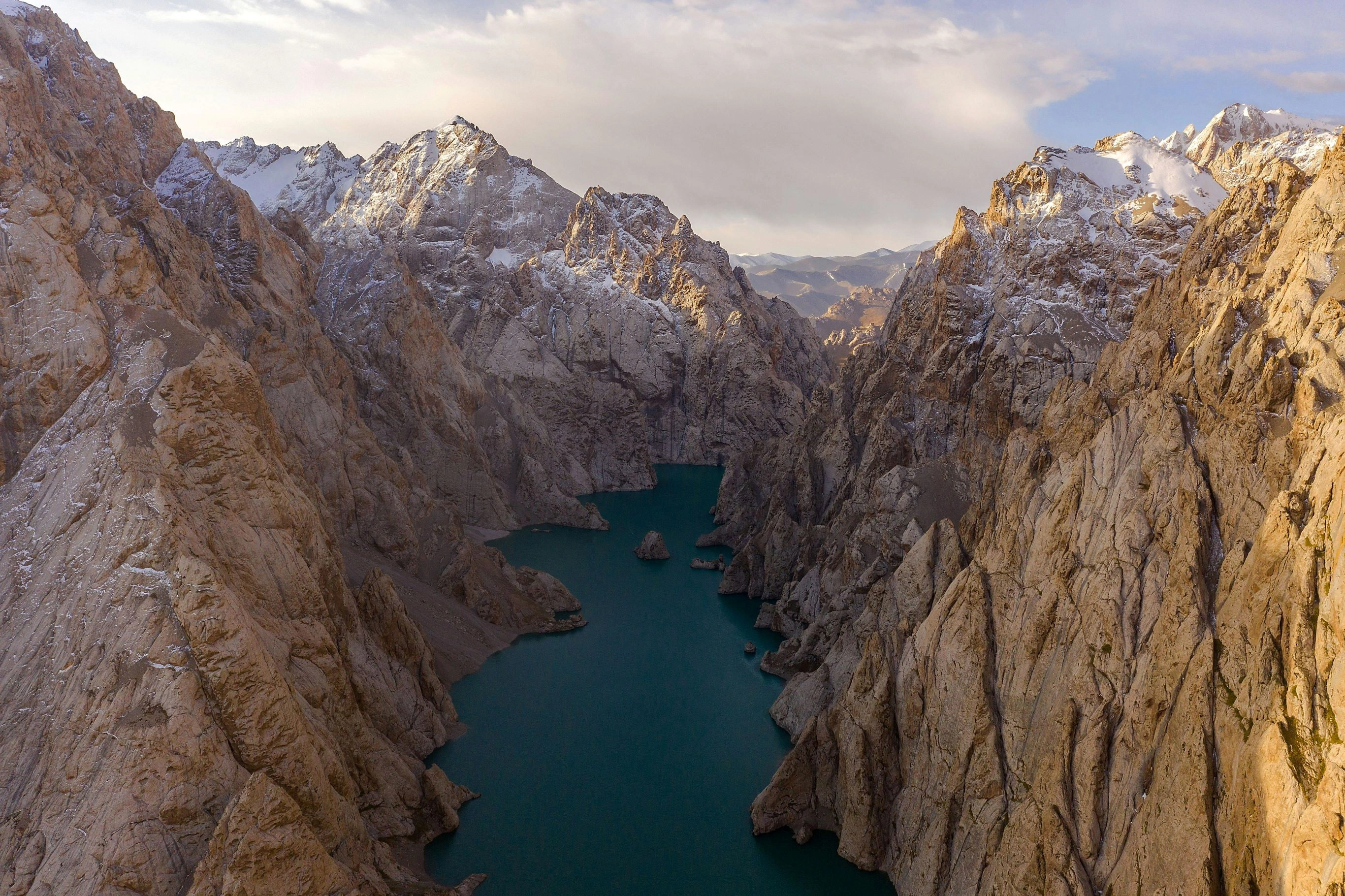 Aerial view of rugged mountain gorge with deep blue alpine lake in Kyrgyzstan.