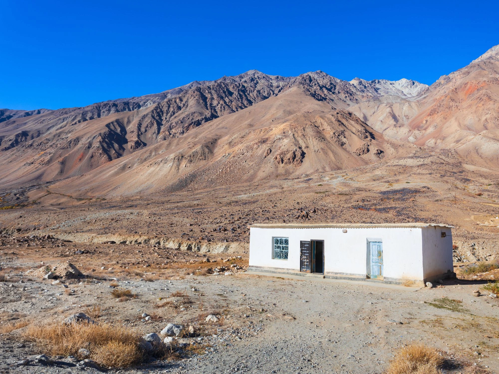 Isolated white roadside building in a rocky, barren mountain landscape near Murghab.