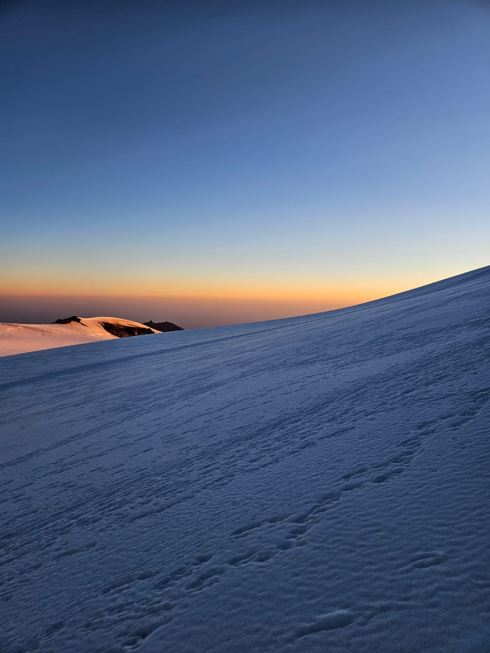 Early morning light over snow-covered slopes of Mount Kazbek, no climbers in view.