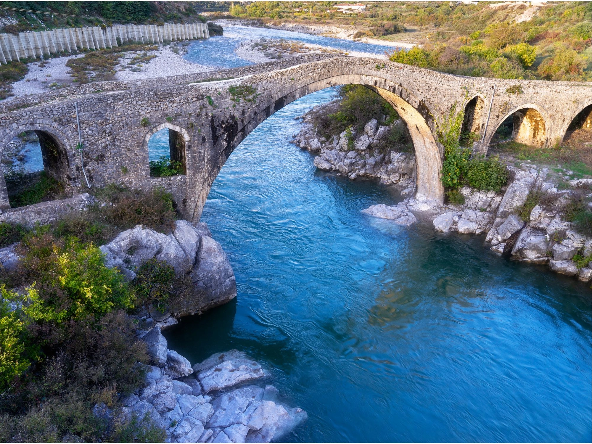 Historic Mesi Bridge crossing the Kir River near Shkoder, Albania, surrounded by nature.