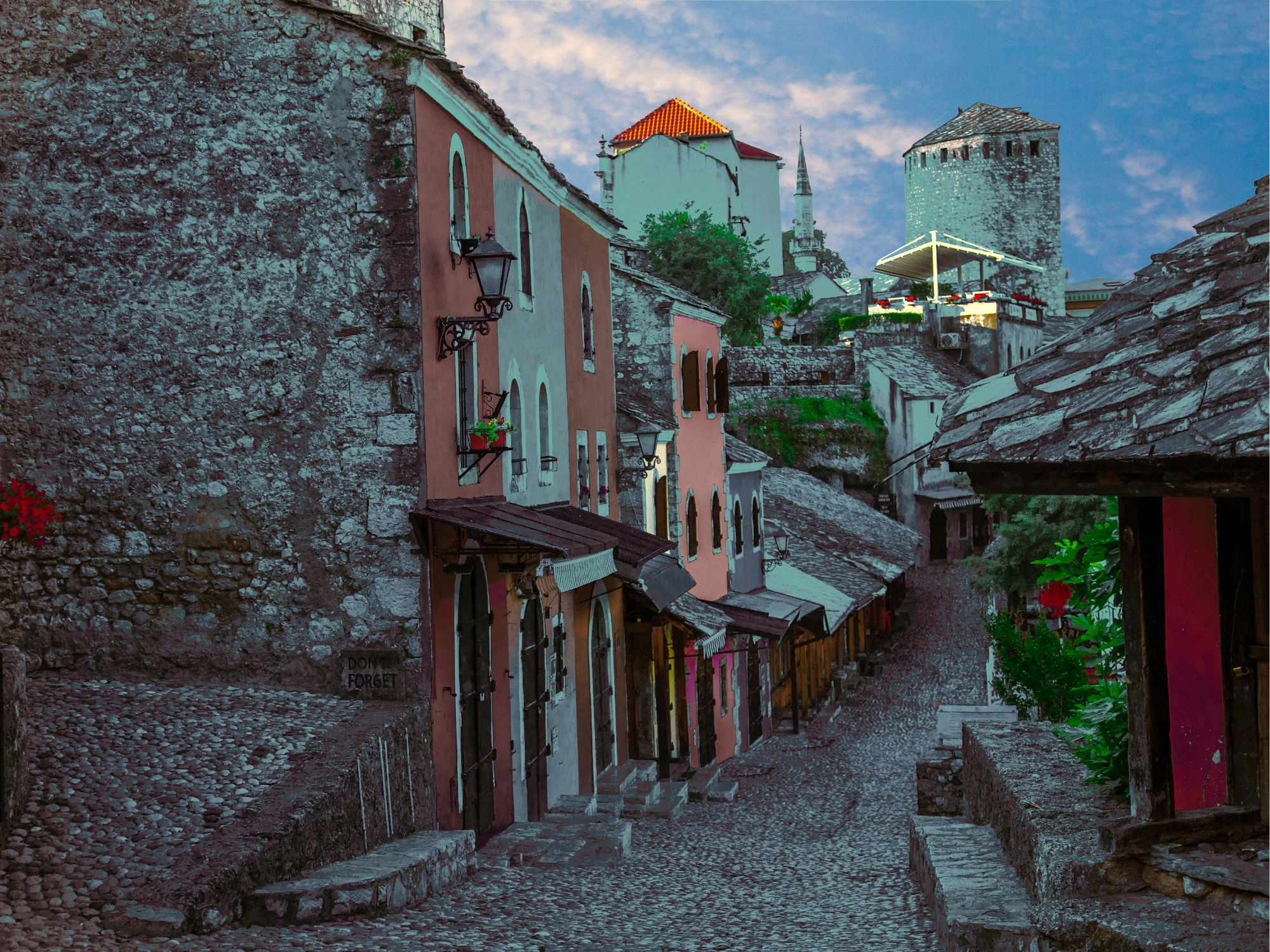 Cobblestone street lined with colorful houses and towers in Old Town Mostar, Bosnia and Herzegovina.