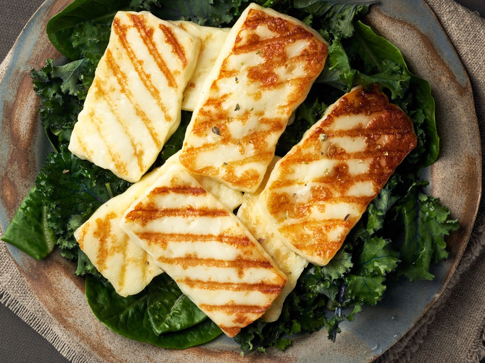 Grilled halloumi slices on a bed of fresh greens, traditional Cyprus cheese dish.