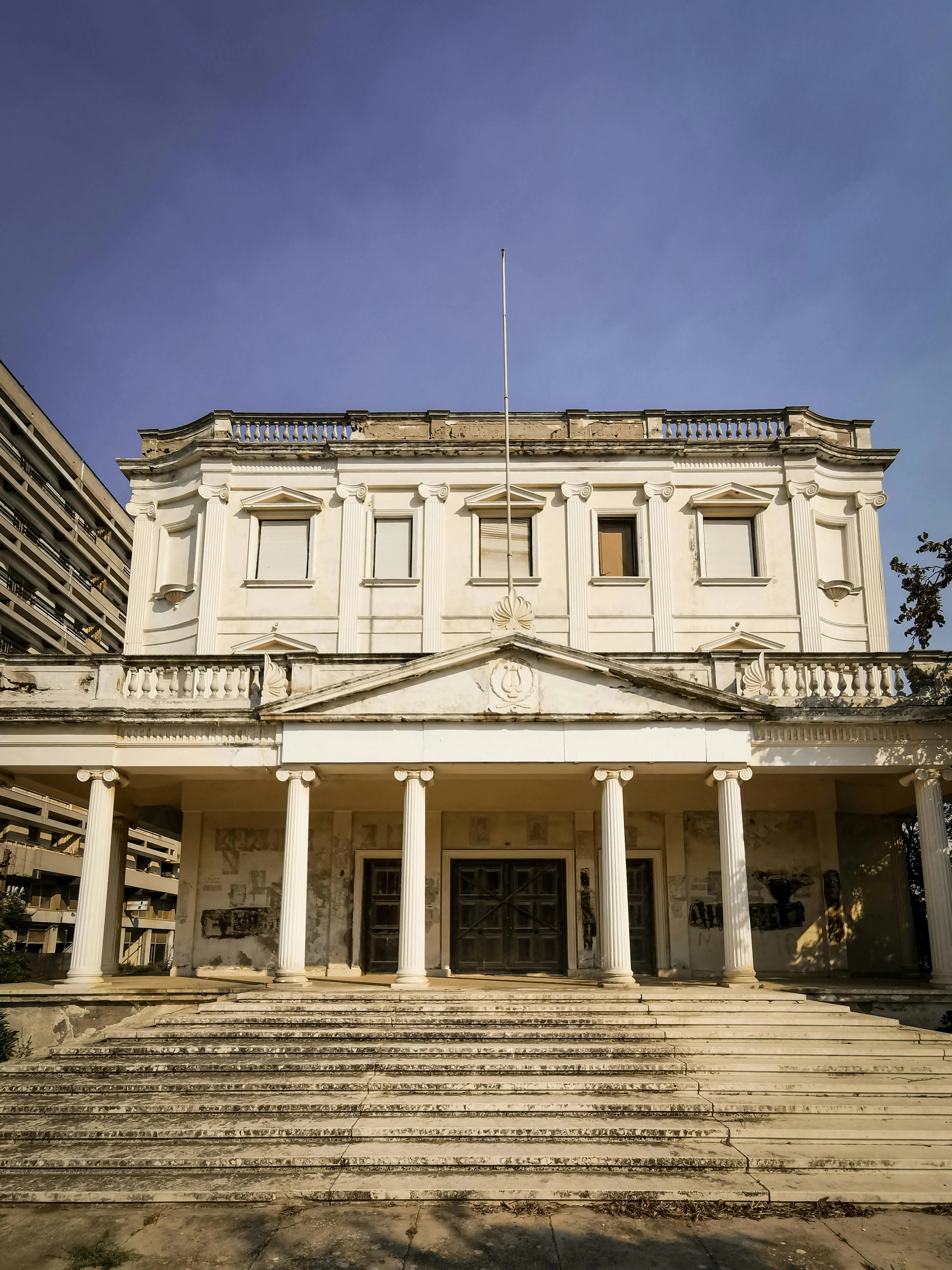 Neoclassical abandoned building in Cyprus with columns and peeling facade.