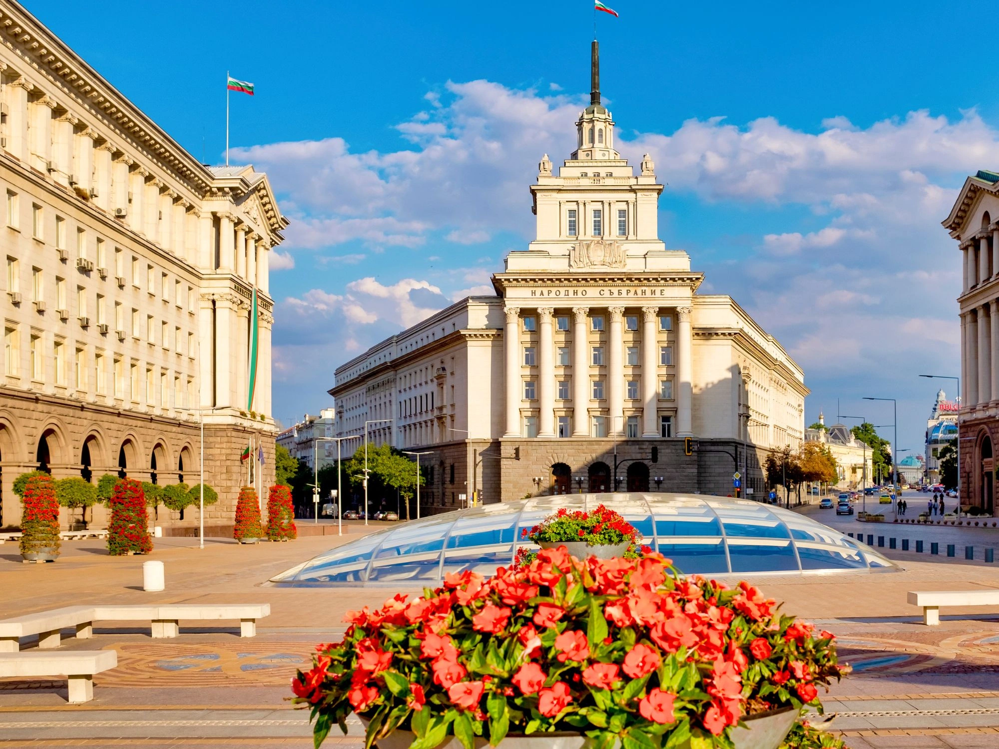 Bulgarian Parliament in Sofia framed by flowers and modern glass dome in the city center.