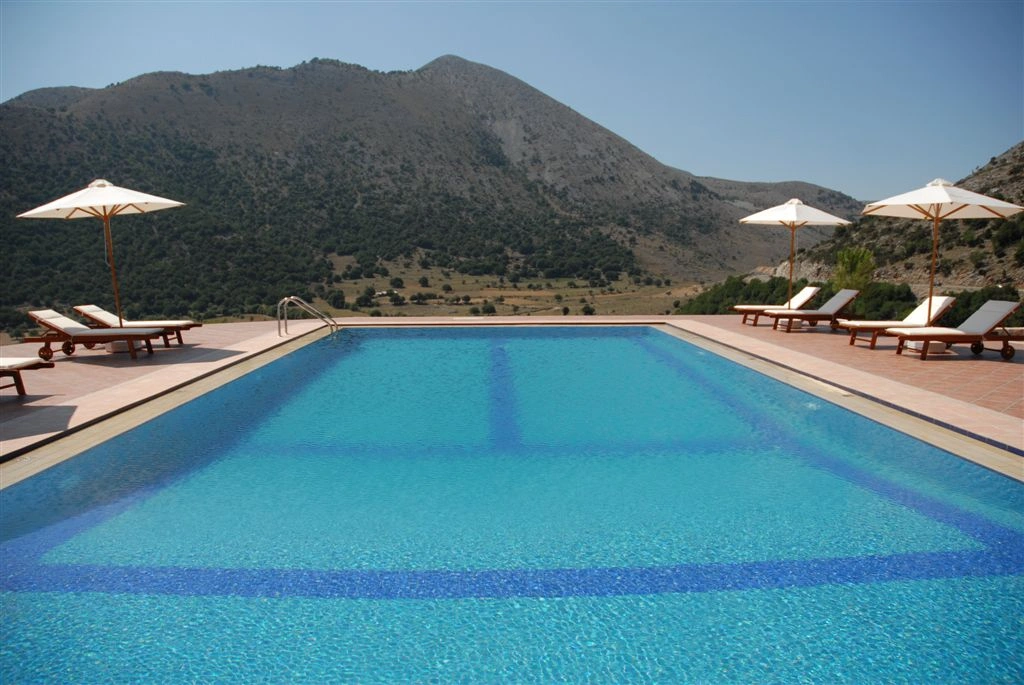 Infinity pool at Lefkoritis resort overlooks Crete’s White Mountains under clear blue skies.