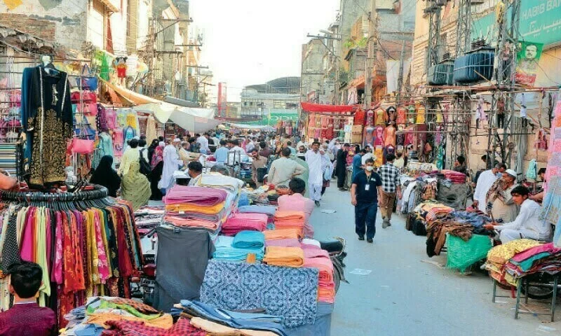 Raja Bazaar colorful stalls and fabrics, bustling shopping street in Pakistan.