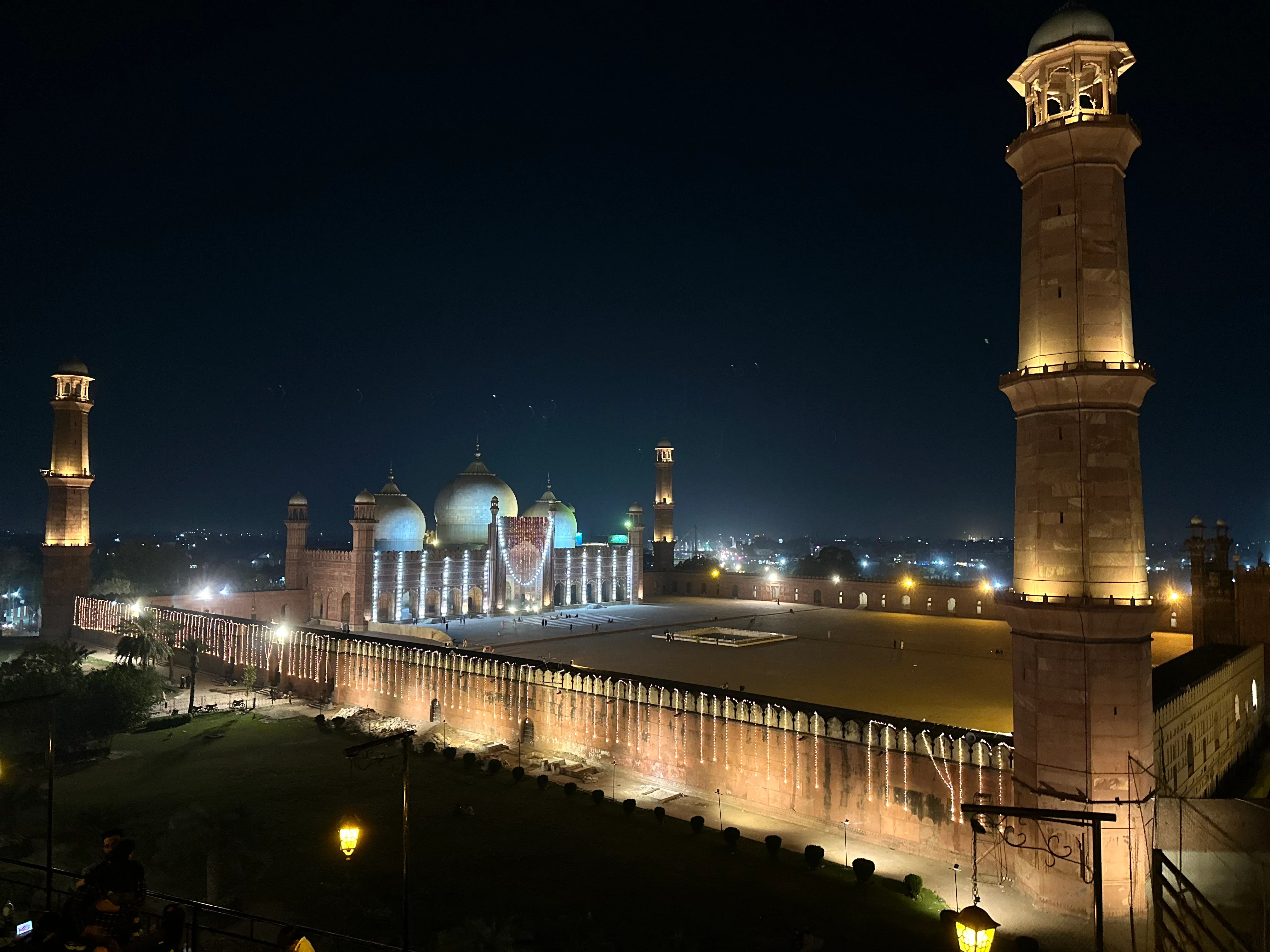 Night view of illuminated Badshahi Mosque Lahore, historic landmark glowing under lights.