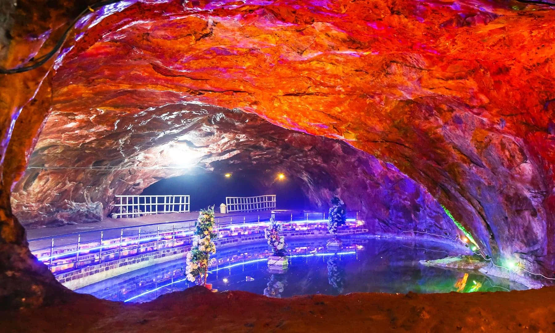 Khewra Salt Mine illuminated tunnel with colorful lights and reflection on water.