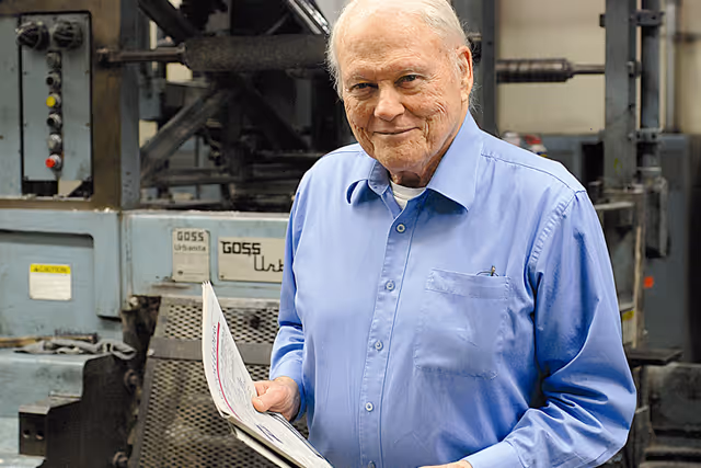 Image of William J. O'Neil standing in front of a printing press
