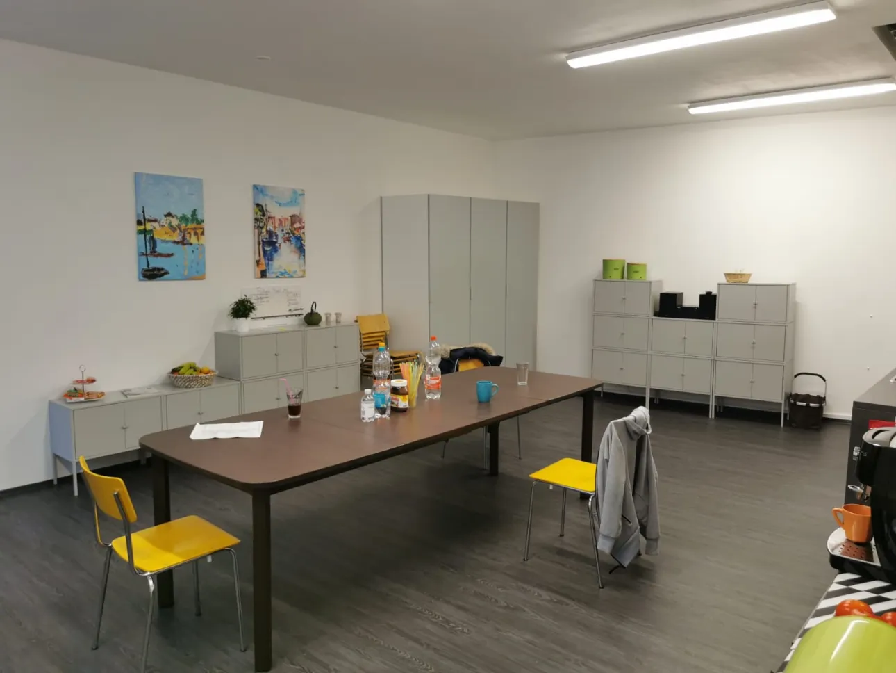 Ein freundlicher Aufenthaltsraum mit einem Tisch und Sitzmöglichkeiten und Schränken und Bildern