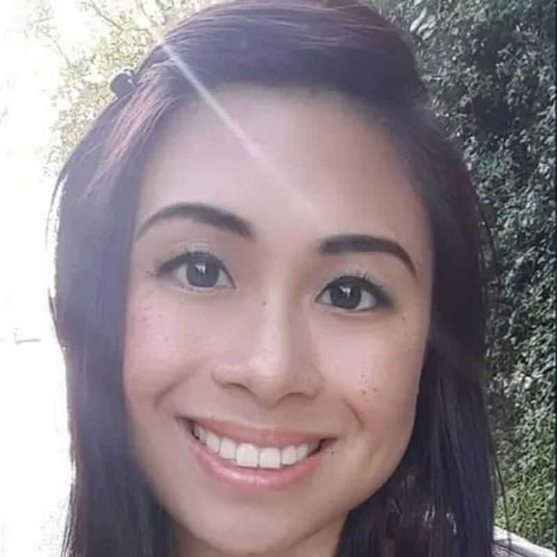 Eine junge Frau mit braunen Haaren lächelt in die Kamera.