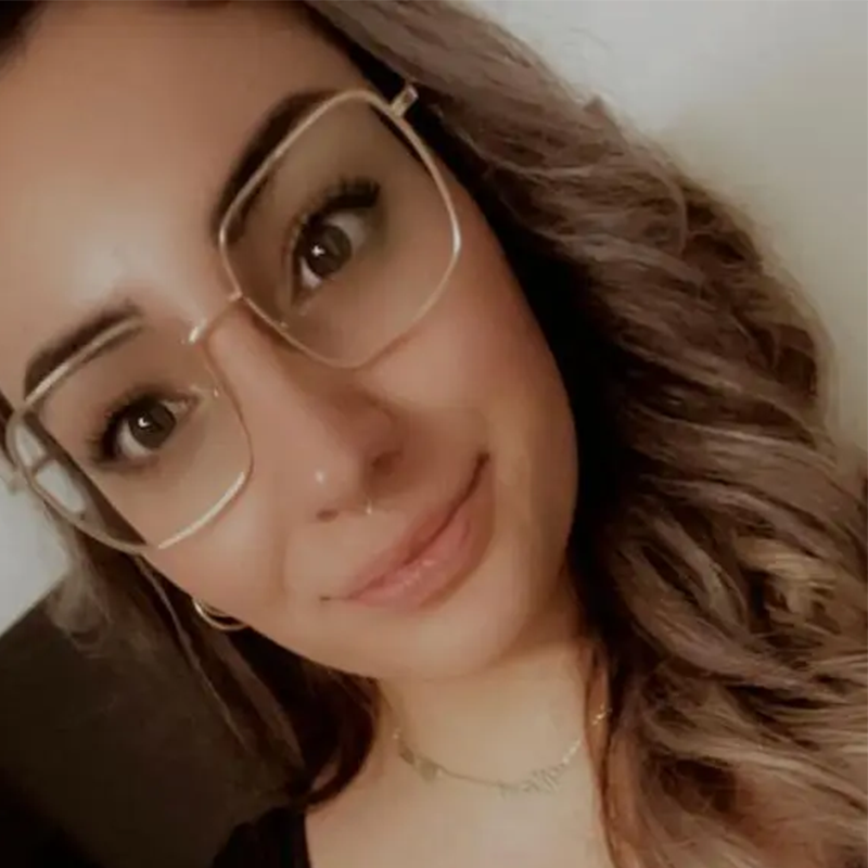 Eine junge Frau mit Brille lächelt in die Kamera.