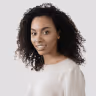 Portrait of a woman with curly hair wearing a light-colored top, smiling gently against a white background.