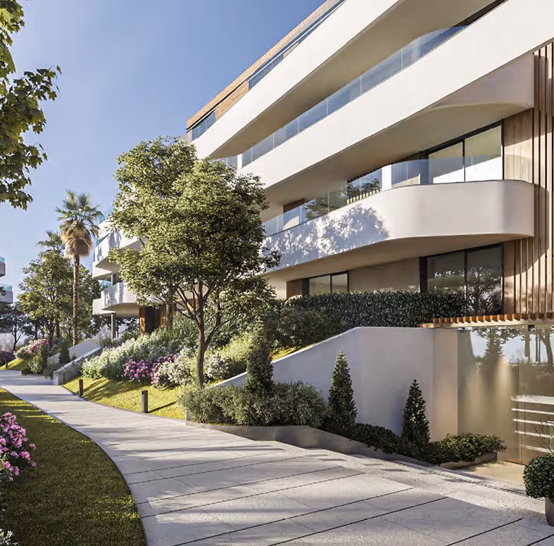 Moderní apartmánový dům s prosklenými balkony, zelení a upravenou cestou na Costa del Sol ve Španělsku.