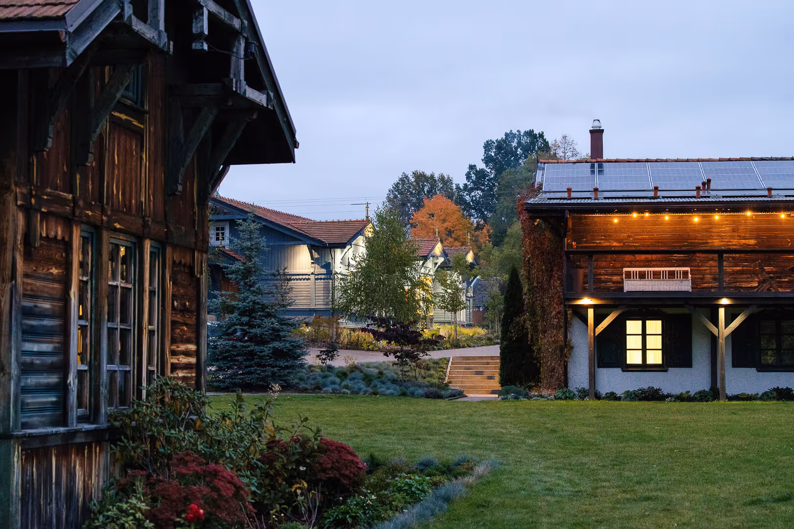 Domy wiejskie pensjonatu w Narewce o zmierzchu z oświetleniem zewnętrznym i panelami słonecznymi na dachu.