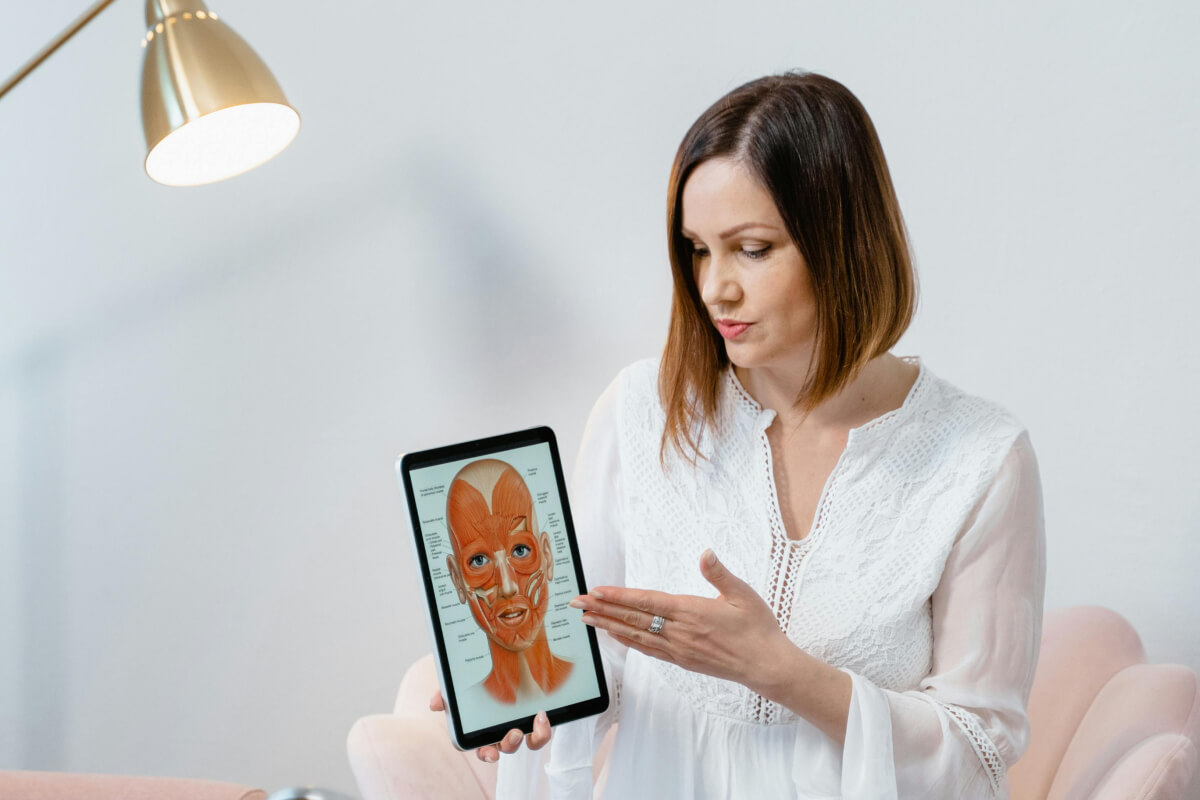 Ärztin zeigt Gesichtszonen auf einem Bild.