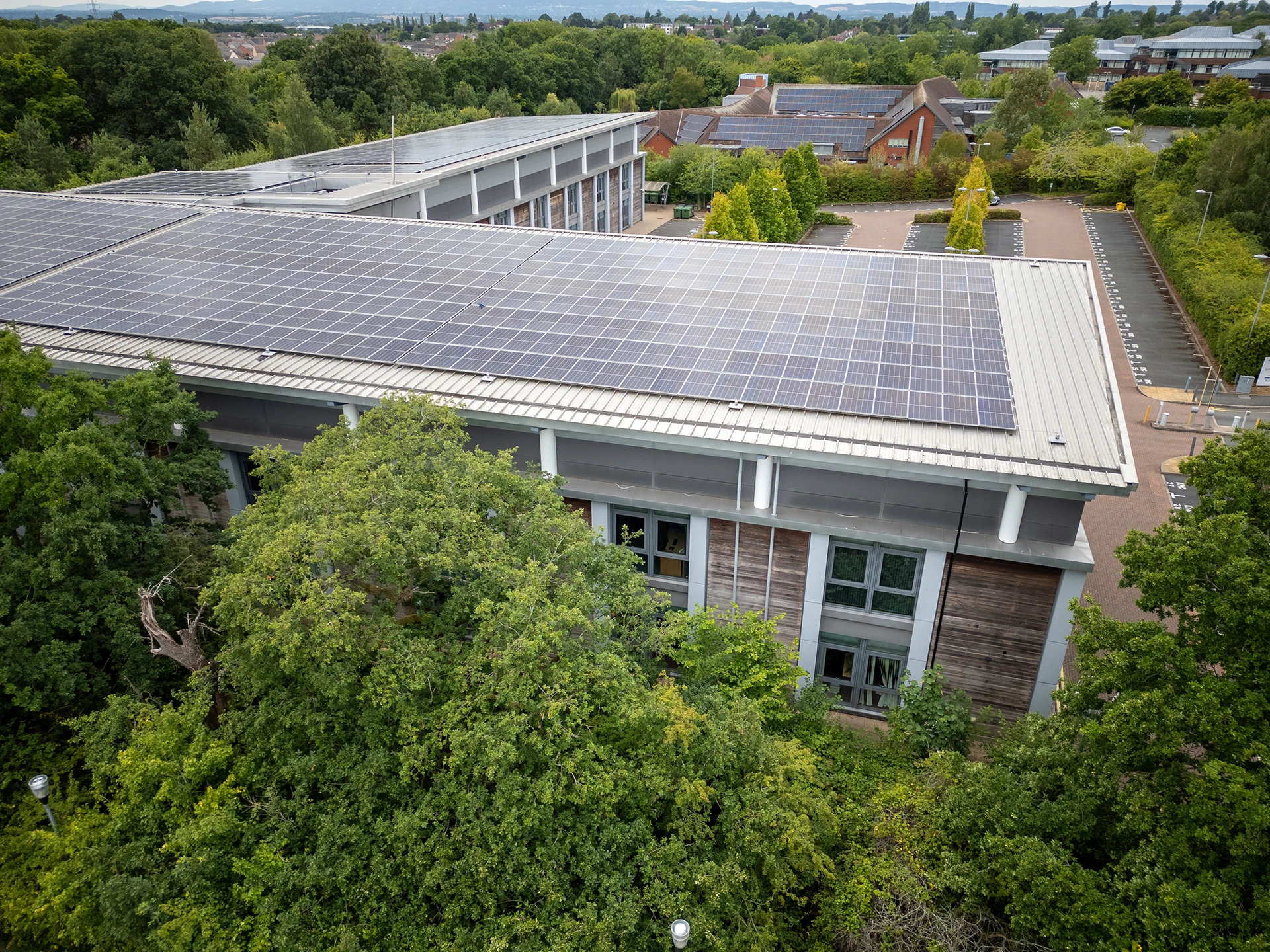 Educational facility with extensive rooftop solar panel array surrounded by mature trees