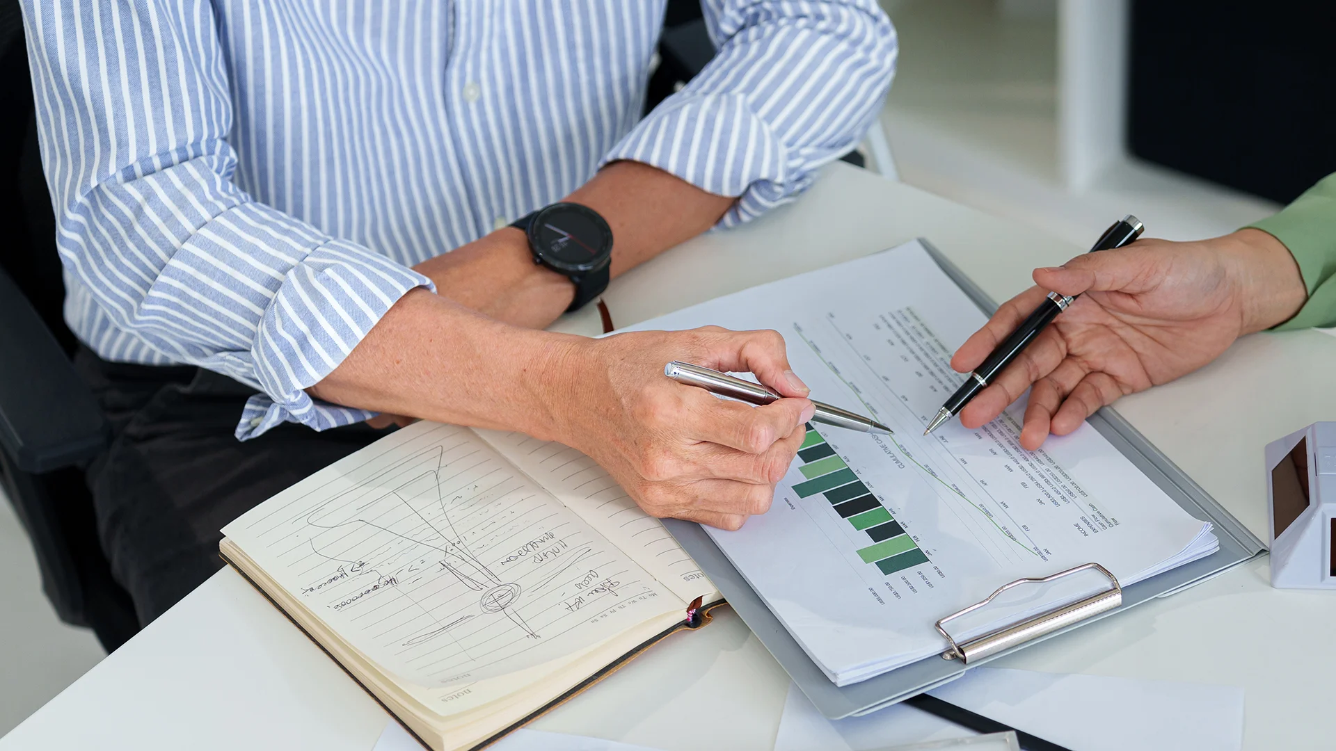 Two people analysing financial data and bar charts during a business meeting.