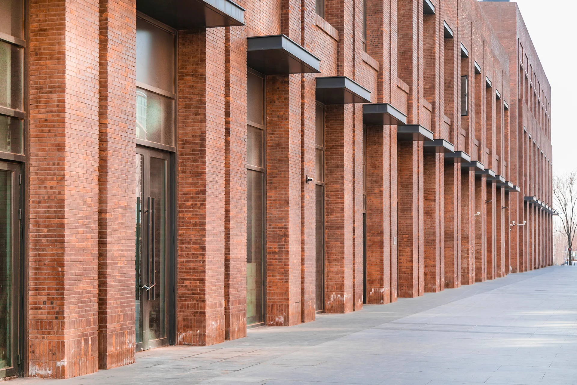 Exterior view of a modern red brick commercial building with tall columns.