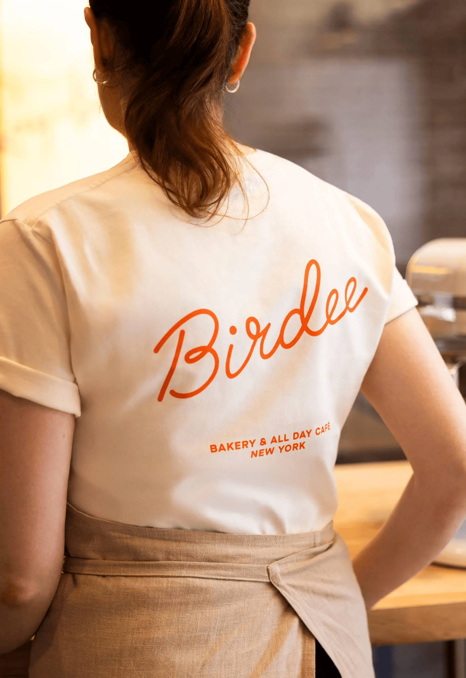 woman wearing cream tshirt with orange Birdee logo on the back