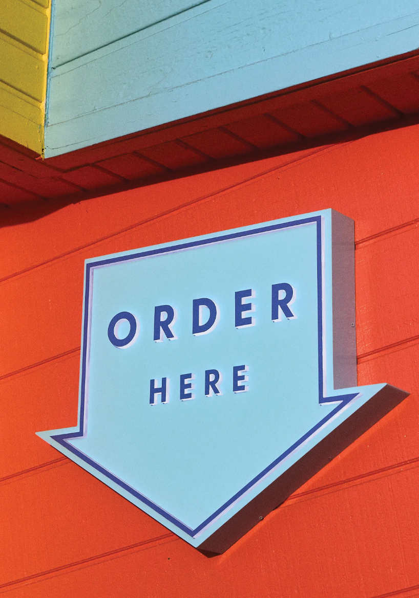 blue arrow sign with "order here" text on red building