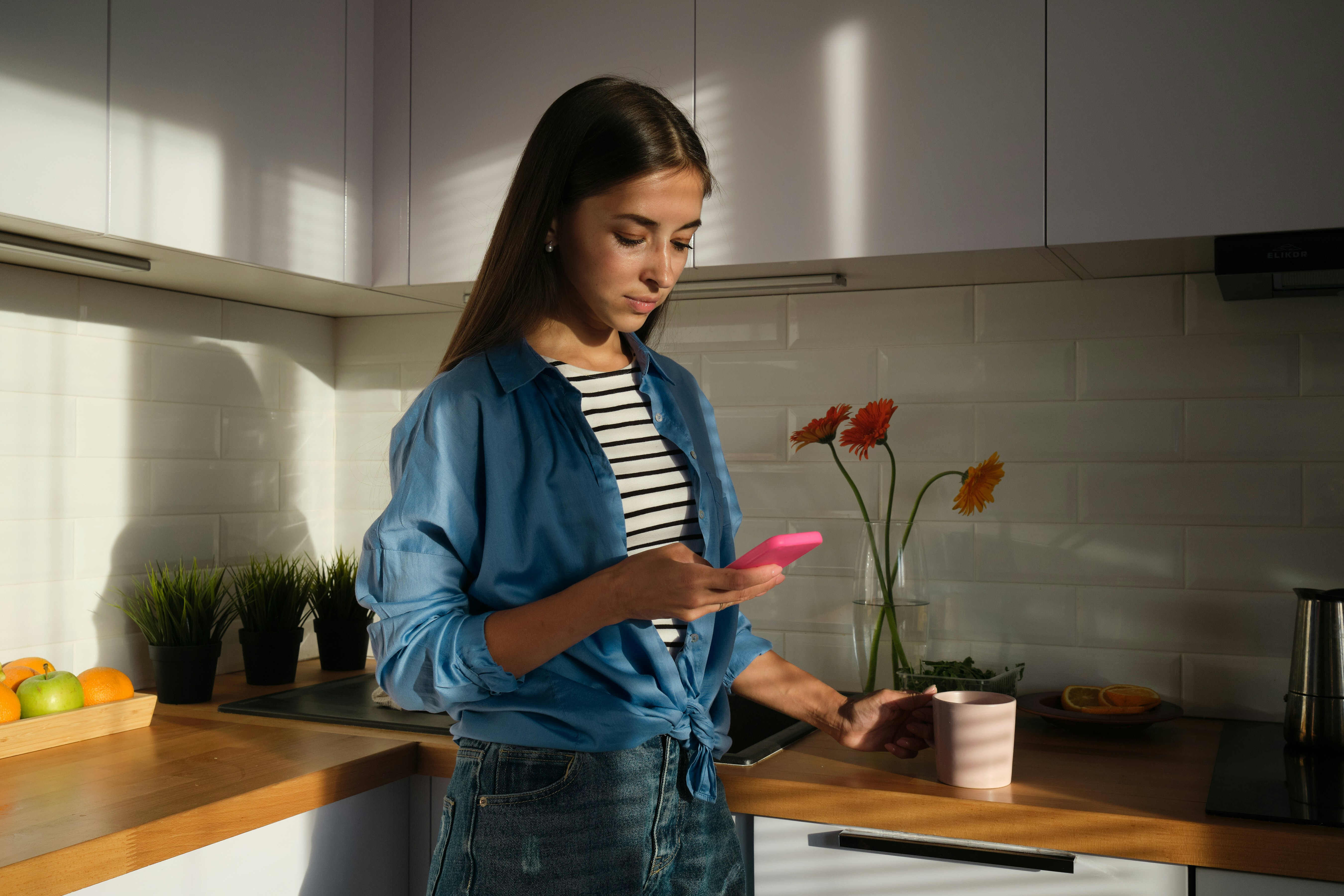 woman looking mobile phone in the kitchen