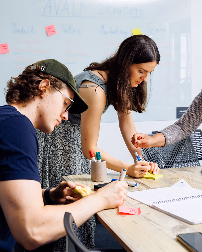 Zwei Personen arbeiten gemeinsam an einem Tisch mit Notizen und Post-its