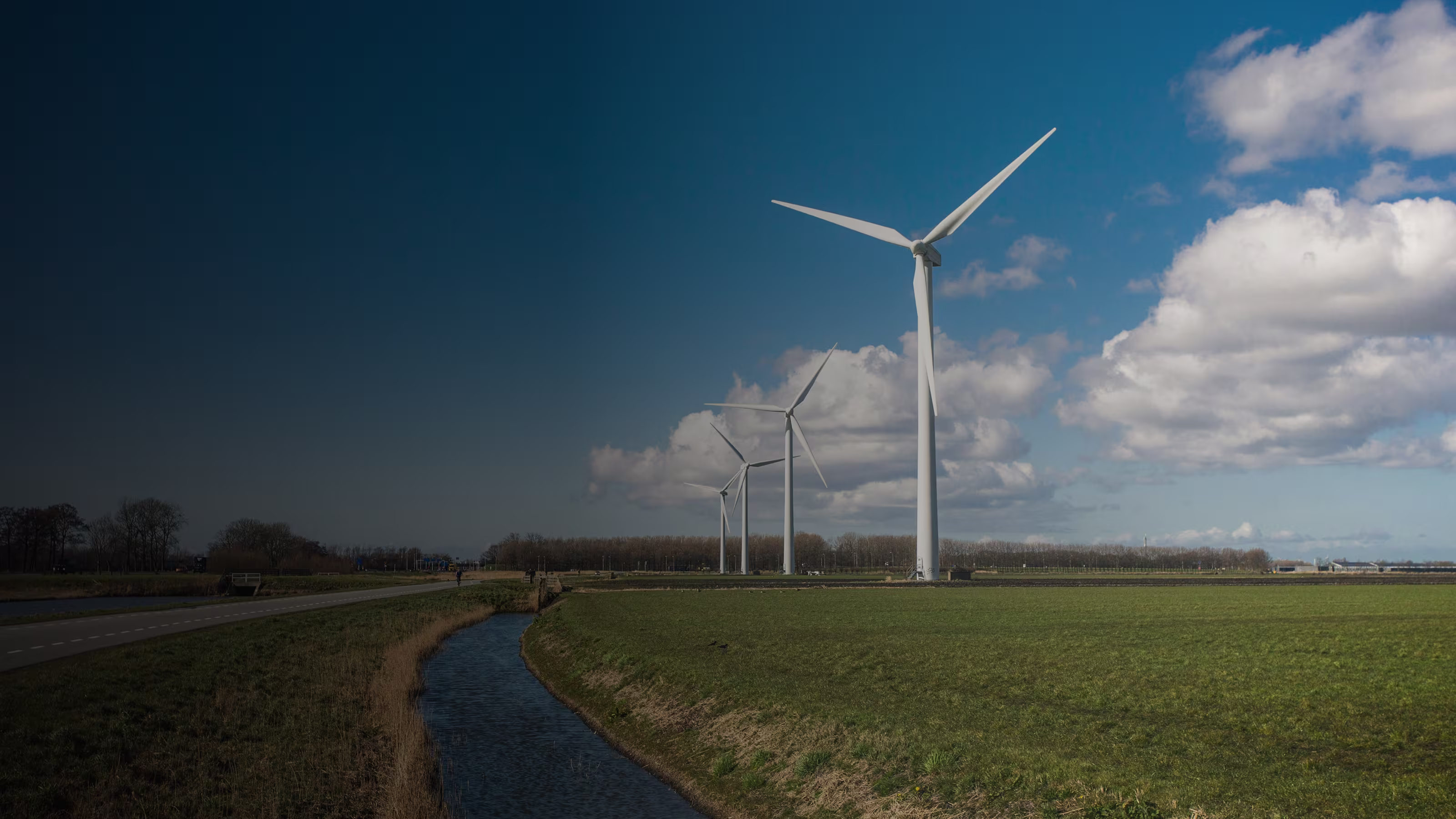 Windräder auf einem Feld unter blauem Himmel mit vereinzelten Wolken