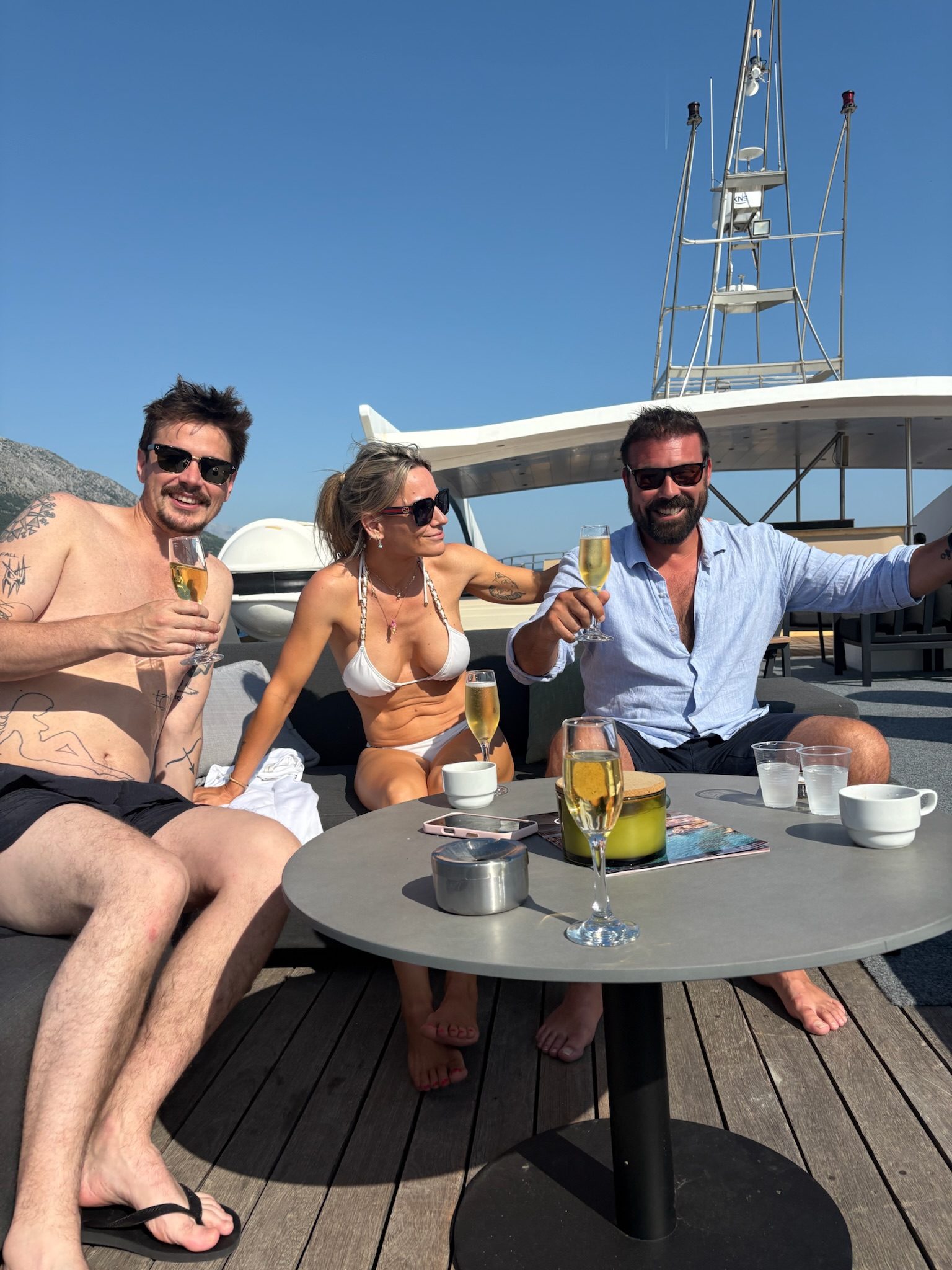 Tres viajeros comparten un brindis en la cubierta de un barco