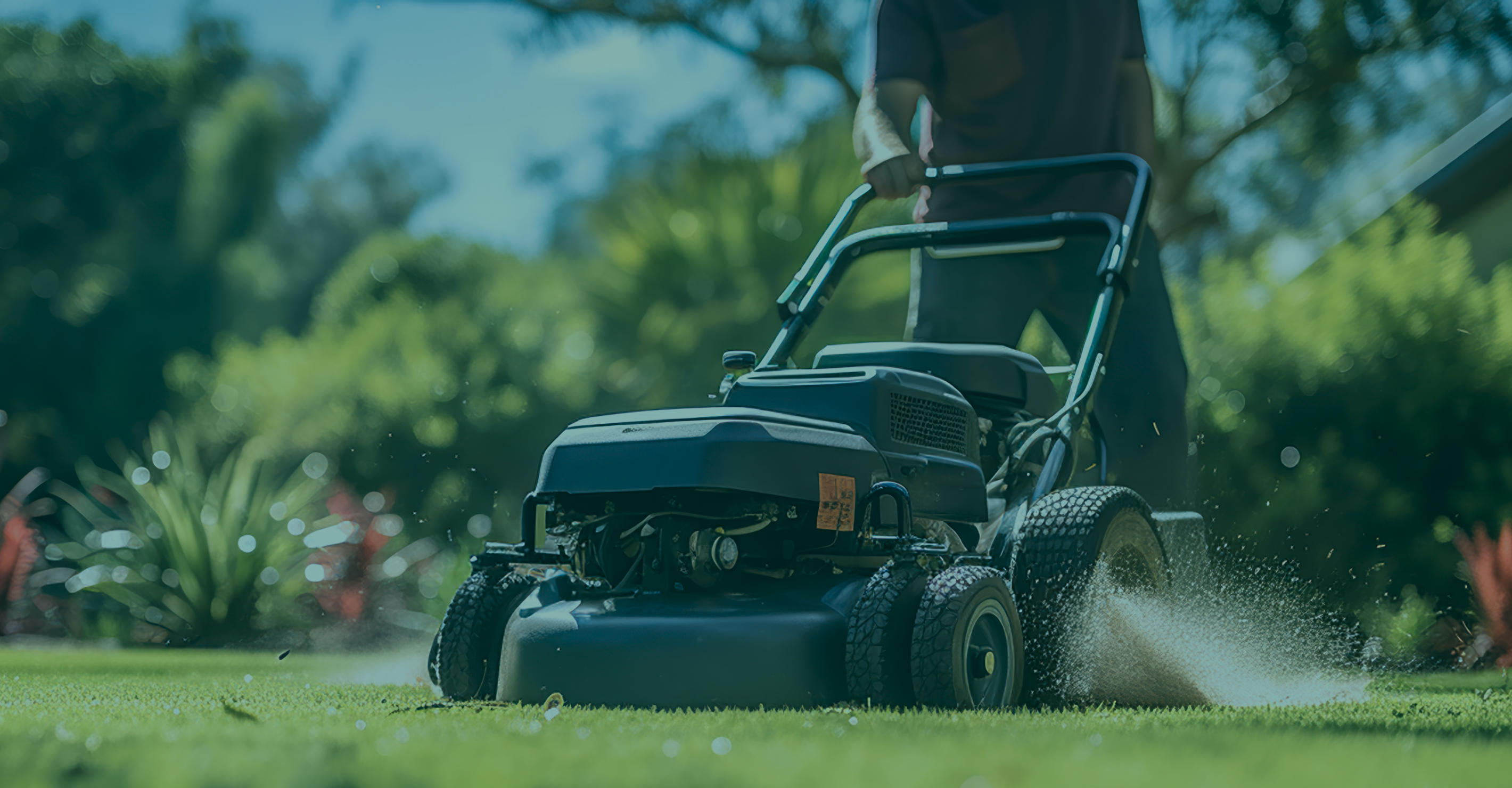 Close-up of a person pushing a lawn mower cutting grass on a sunny day.
