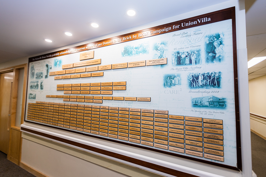 Large recognition wall plaque titled 'Brick by Brick Campaign for Union Villa' with donor names and historical photos.