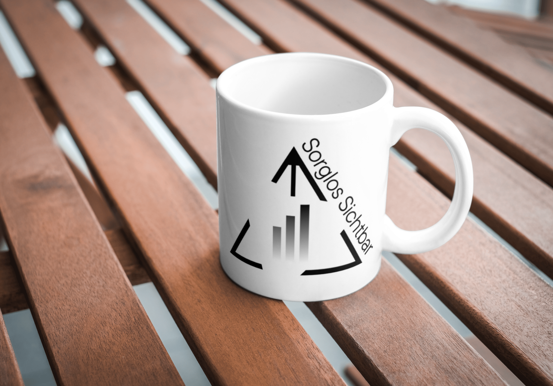„Mockup mit Tasse im Sorglos-Sichtbar-Design – Logo auf weißer Keramiktasse, fotografiert auf Holztisch.