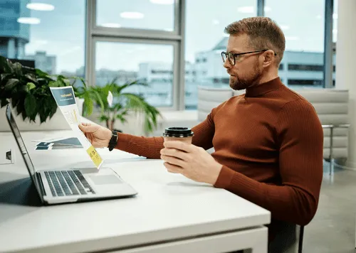 Twee bureaus met platte computerschermen, toetsenborden en een zwart bureaustoel in een kantoorruimte.