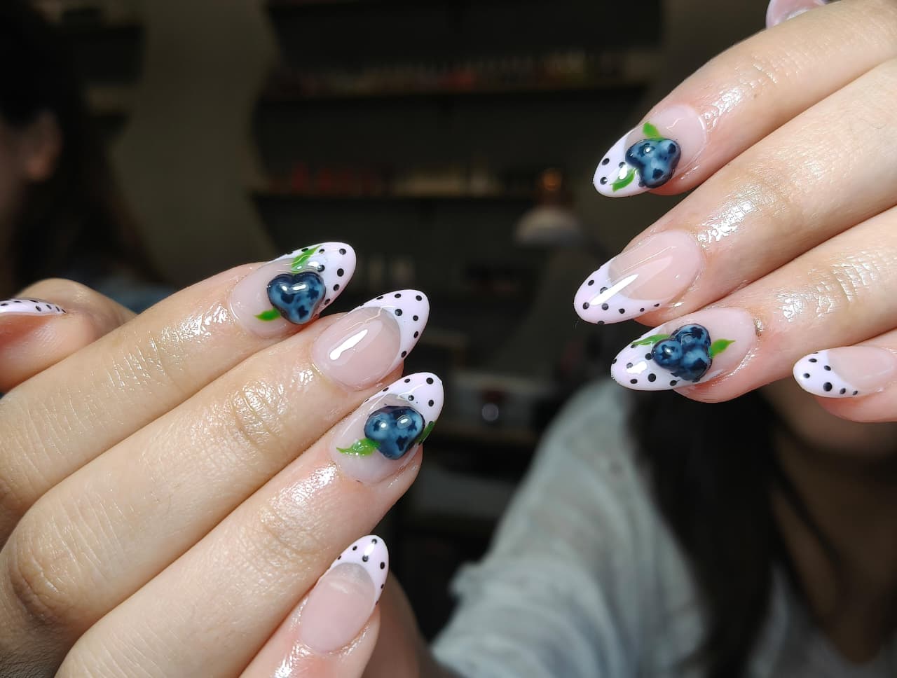 Primer plano de uñas soft gel  con diseño de lunares y nail art 3D de arándanos.