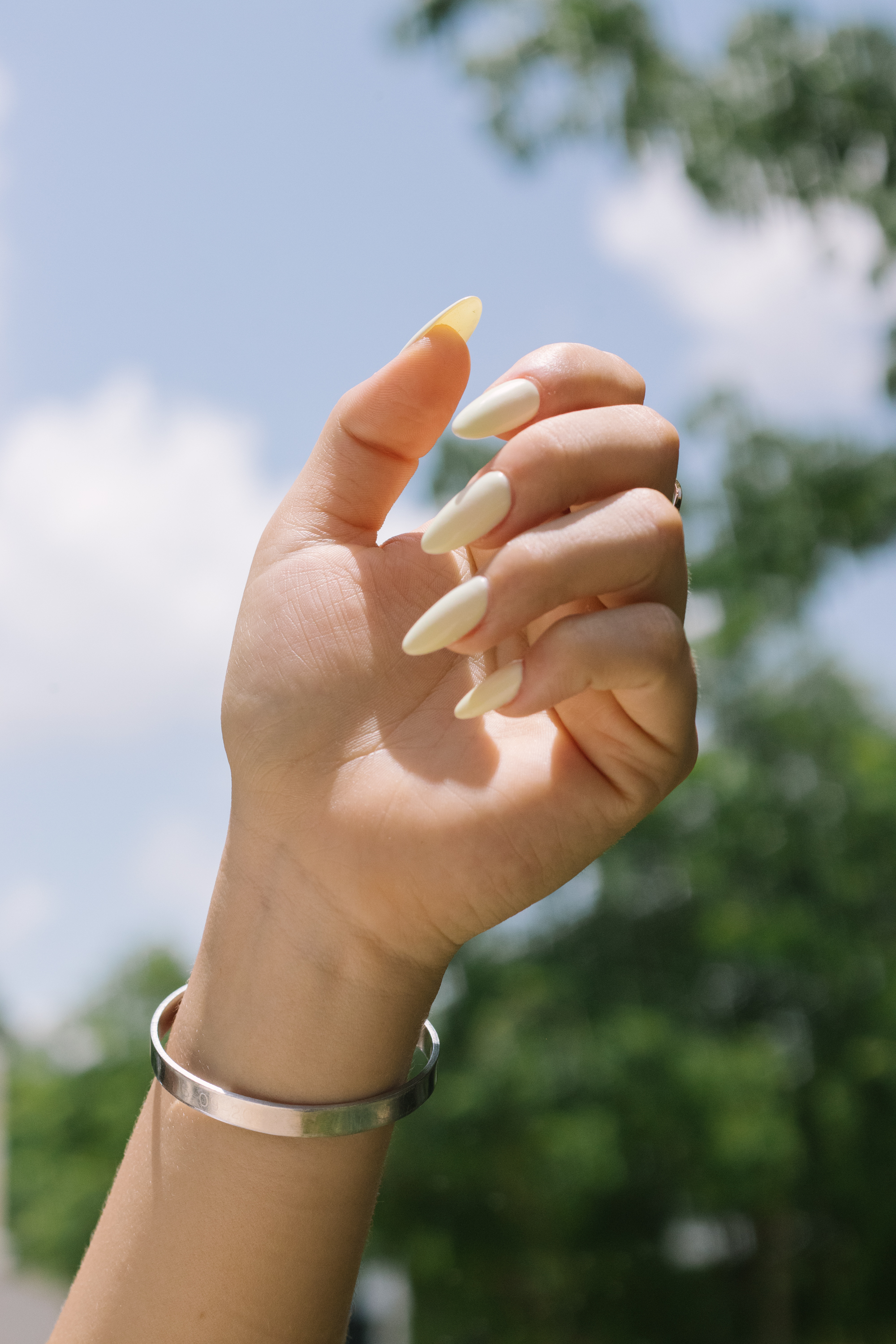 Mano al aire con uñas soft gel largas almendradas color crema, con acabado elegante y natural.