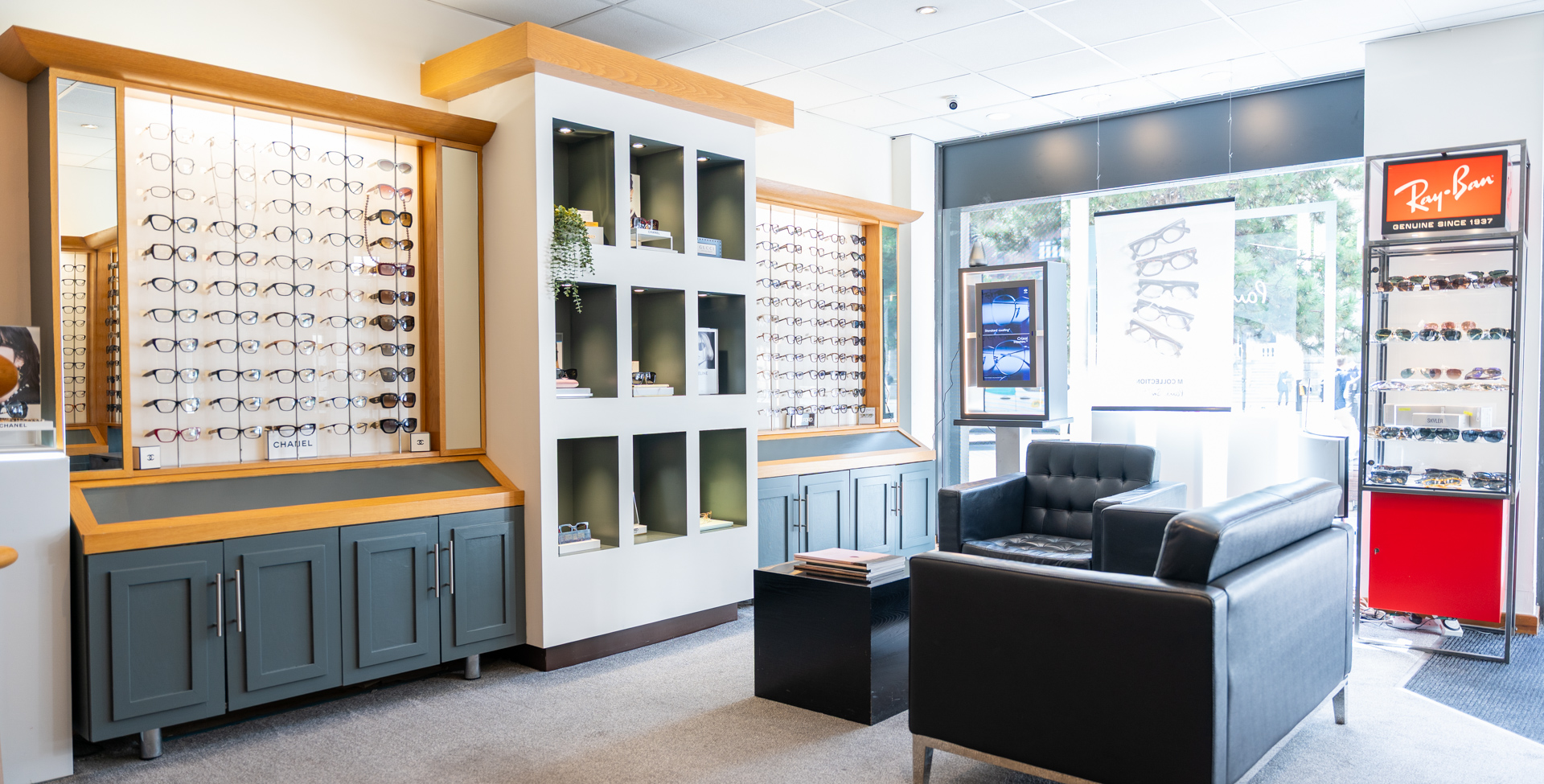 Modern eyeglasses retail store with wooden displays, seating area, and Ray-Ban signage