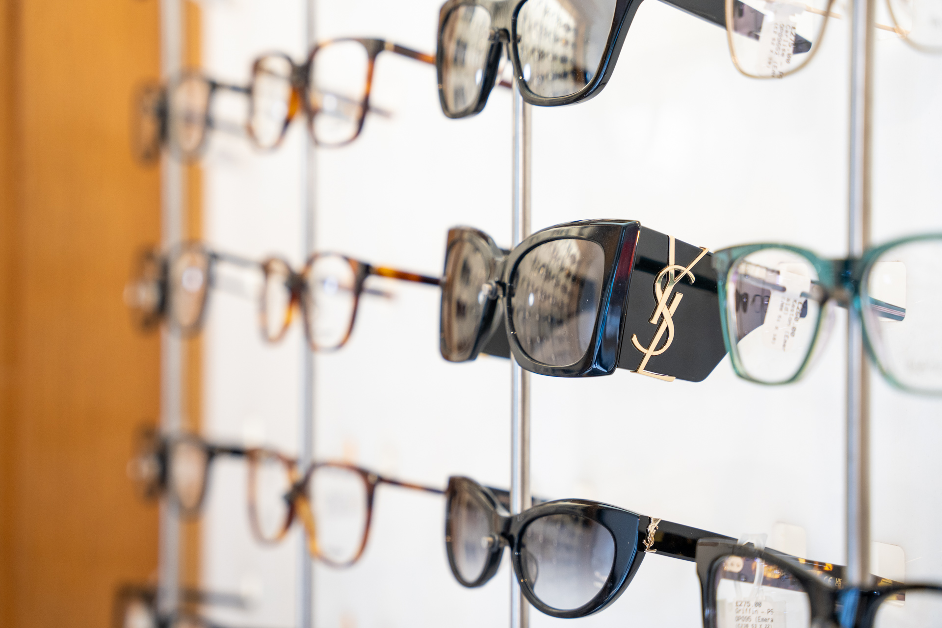 Collection of eyeglasses and sunglasses displayed on store shelf with designer branding