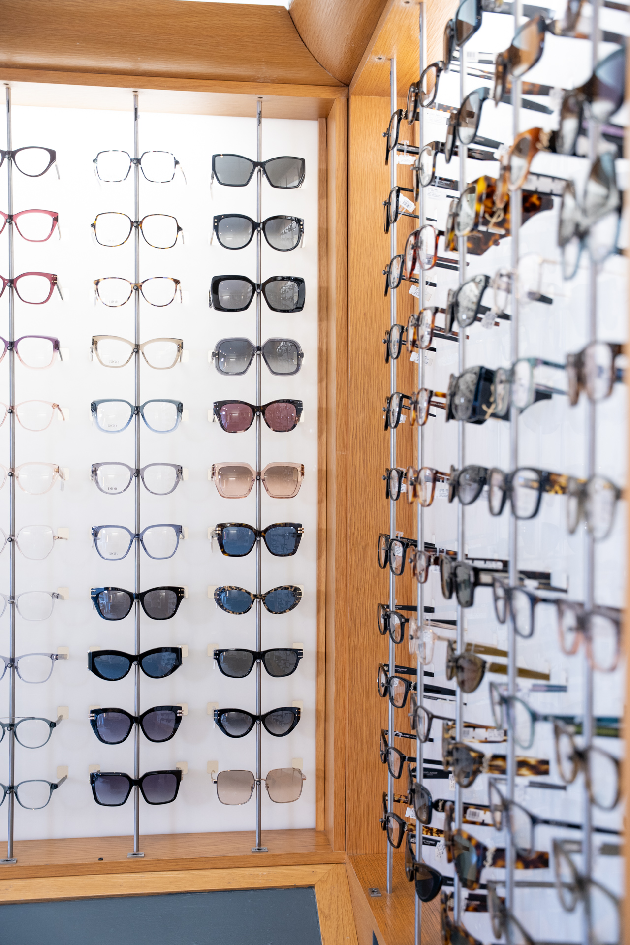 Eyeglass display with wooden frames showing various prescription glasses and sunglasses styles