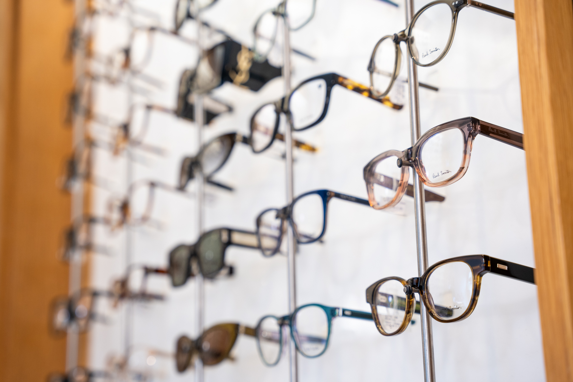 Display of various eyeglasses and sunglasses on metal stands in an optical shop.