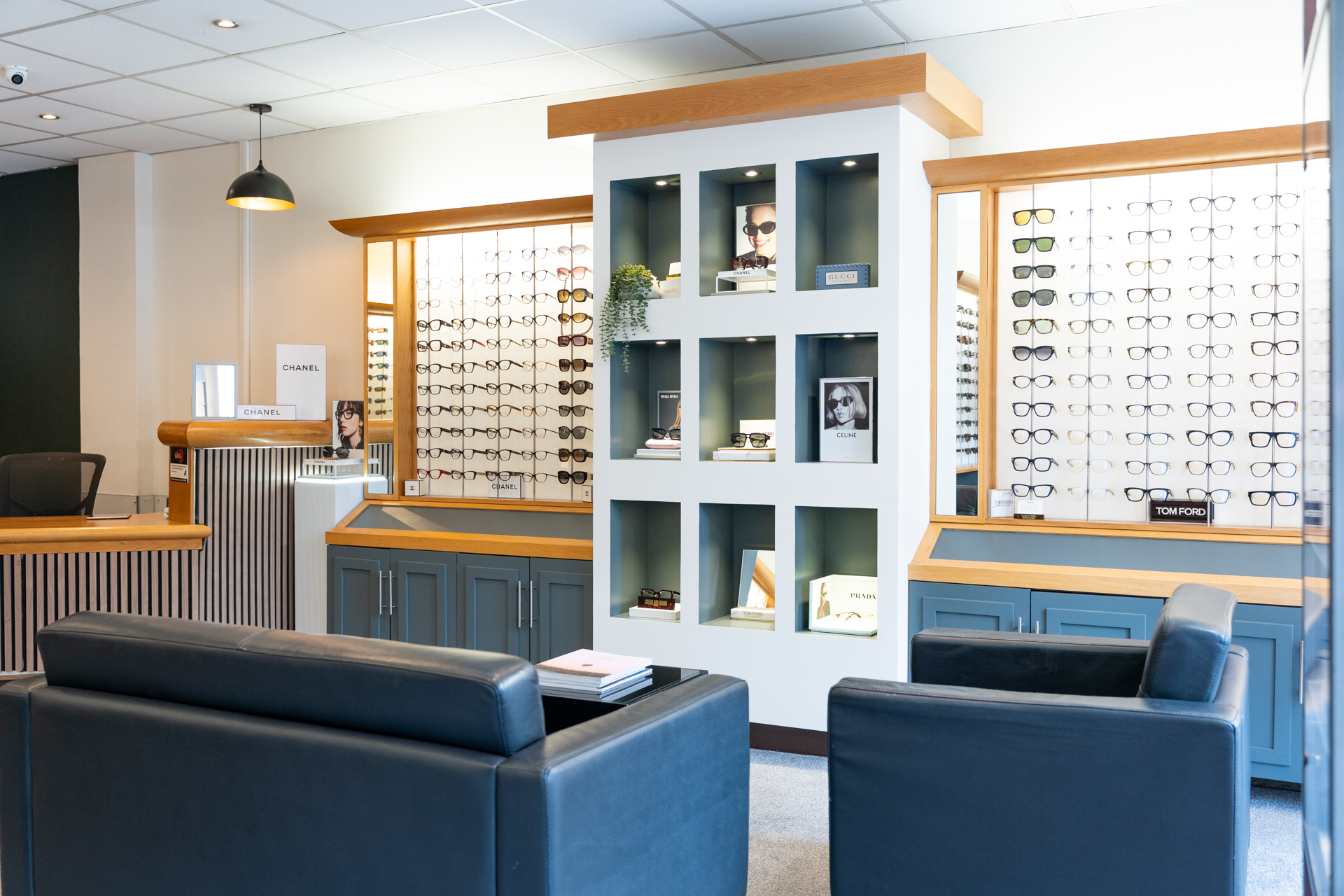 Modern eyewear store interior with wooden displays, designer frames, and blue seating area.