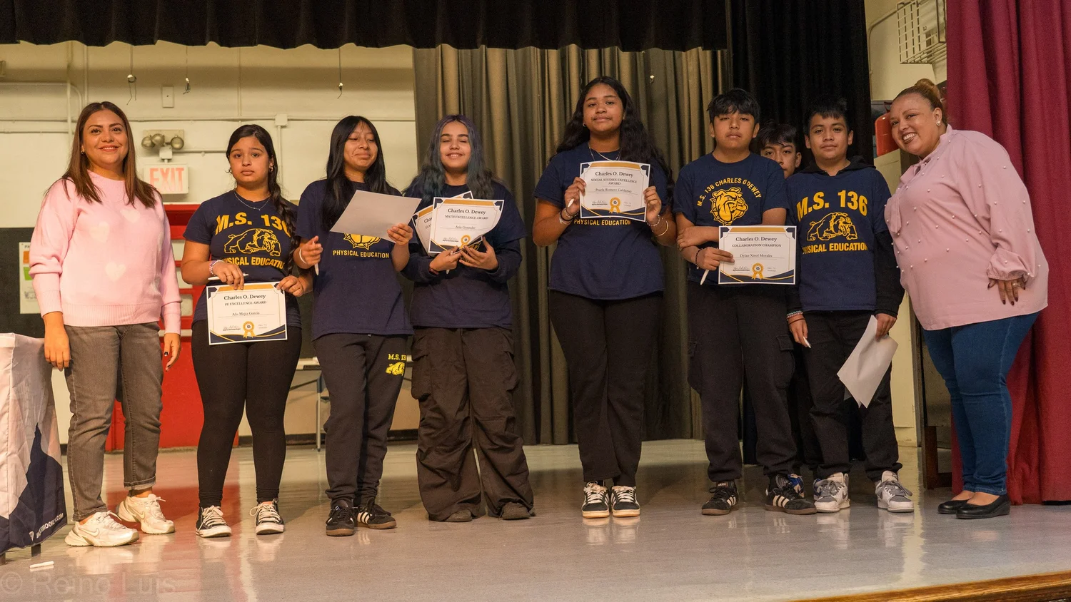 MS 136 students holding certificates on stage at award ceremony
