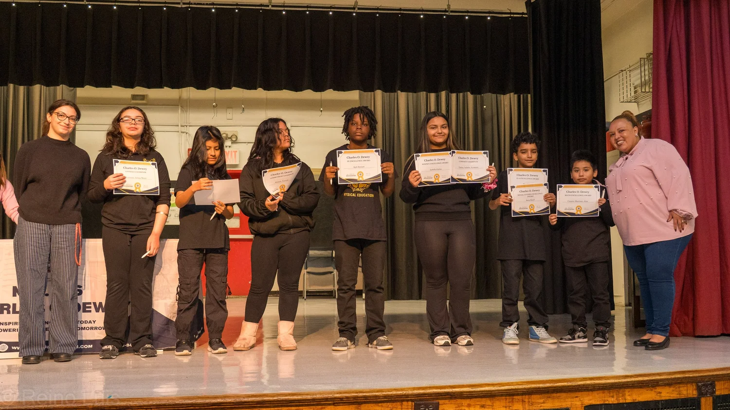 Students holding certificates on stage during a school award ceremony