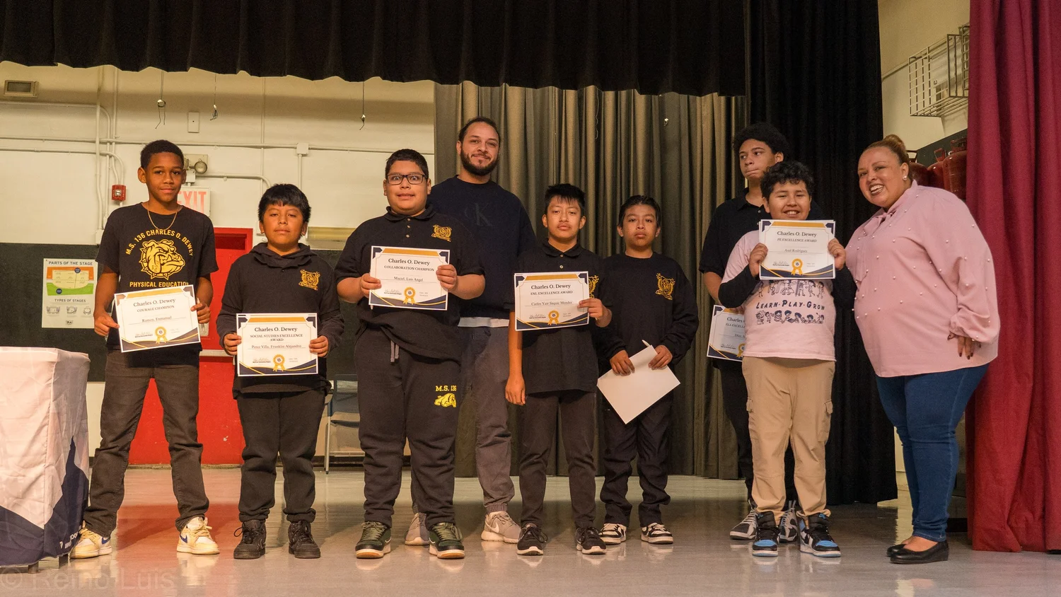 Students and staff holding Charles O. Dewey award certificates on stage