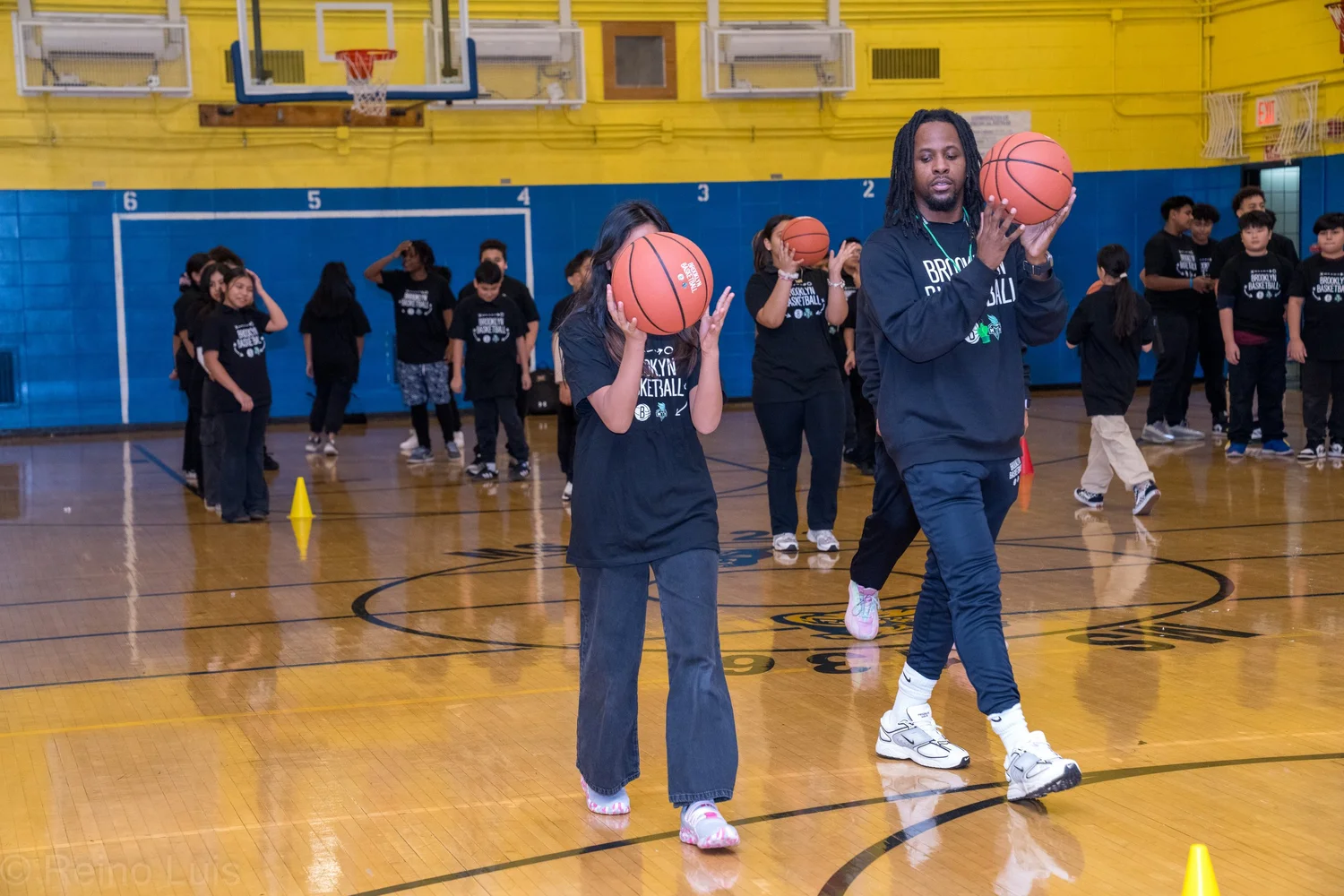 Students and coach practicing basketball drills in school gymnasium