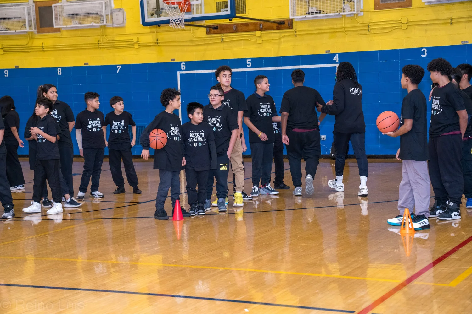 Students participating in a Brooklyn Basketball clinic in school gymnasium