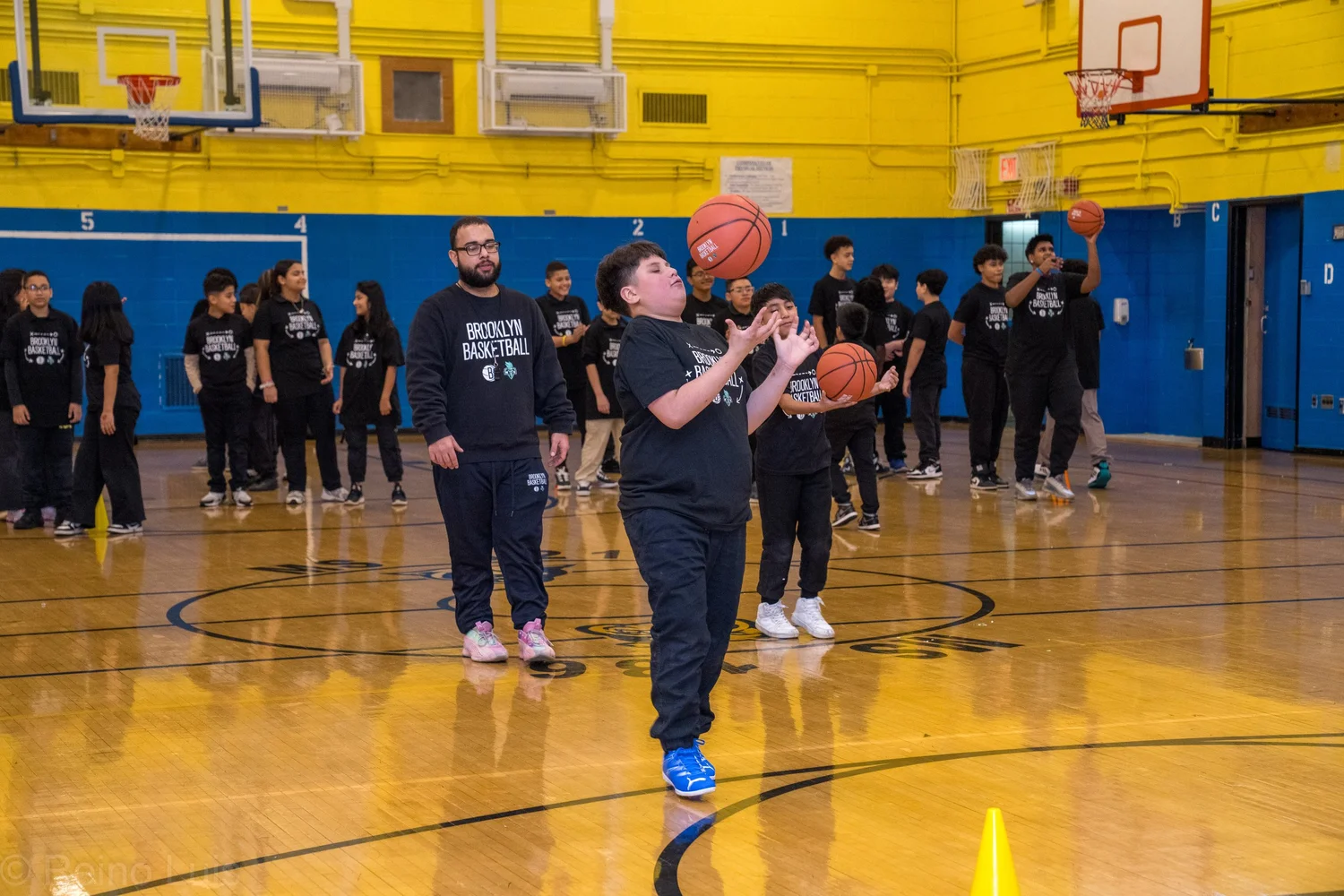 Student catching a basketball during Brooklyn Nets gym program visit